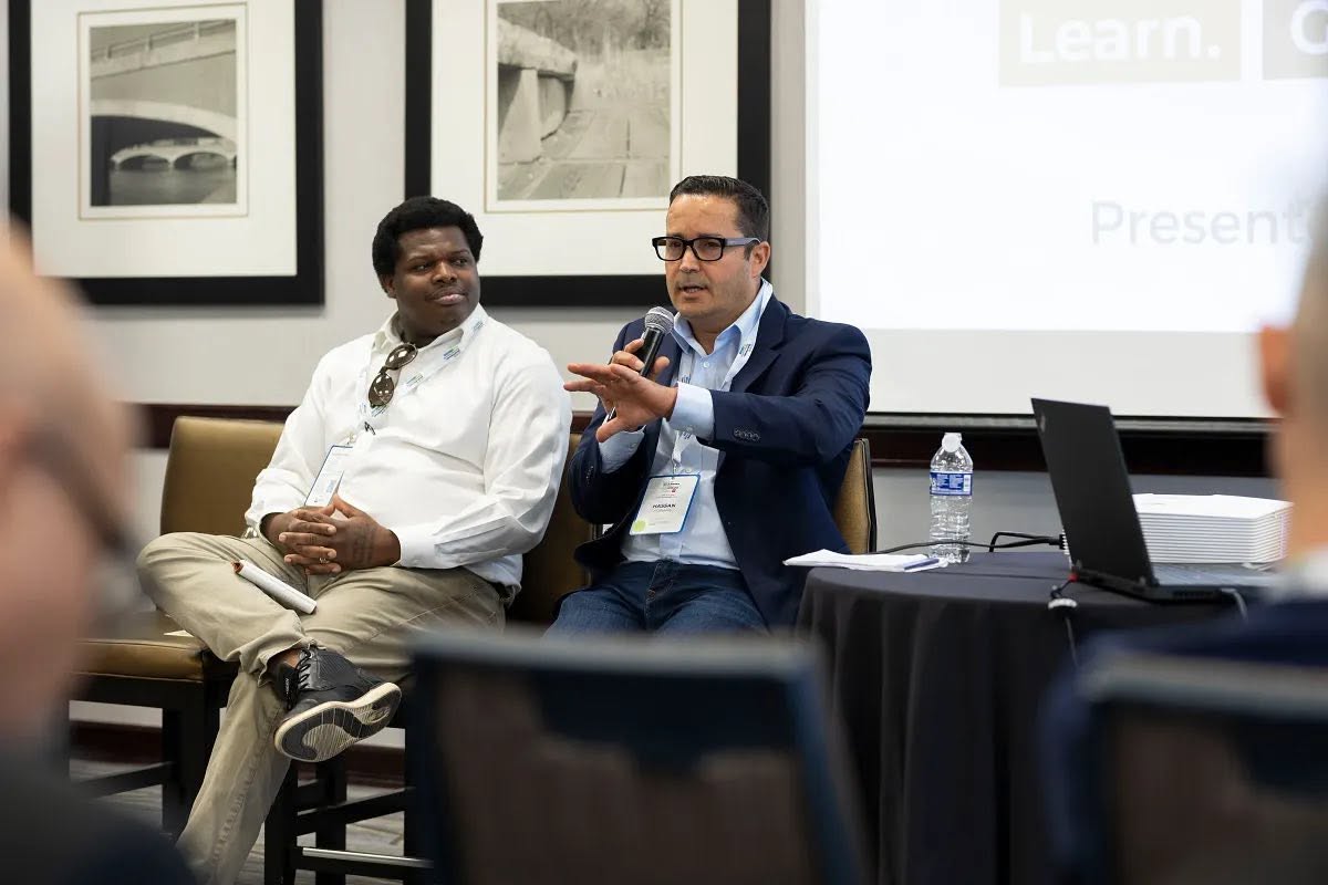 Hassan Atarmal speaking into a microphone during a business panel discussion