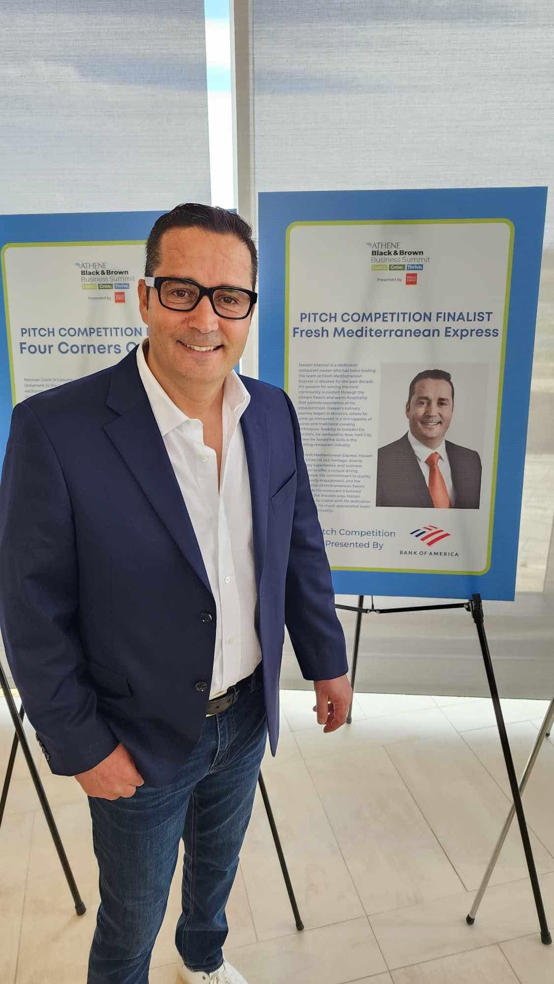 Hassan Atarmal beside the Fresh Mediterranean Express pitch competition finalist display